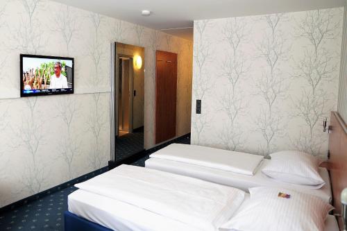 two beds in a room with a tv on the wall at bonjour Tagungshotel Stuttgart-Gerlingen in Gerlingen