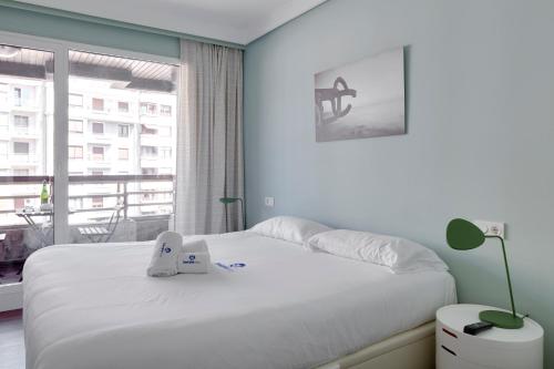 Un dormitorio con una cama blanca grande y una ventana en Koxka - Basque Stay, en San Sebastián
