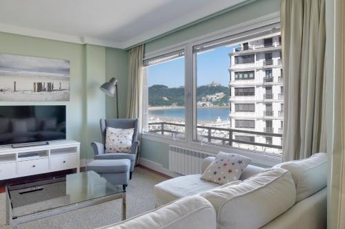 ein Wohnzimmer mit einem Sofa und einem großen Fenster in der Unterkunft Koxka - Basque Stay in San Sebastián