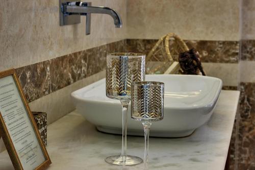 two wine glasses sitting on a counter next to a sink at Lake Pichola Hotel in Udaipur