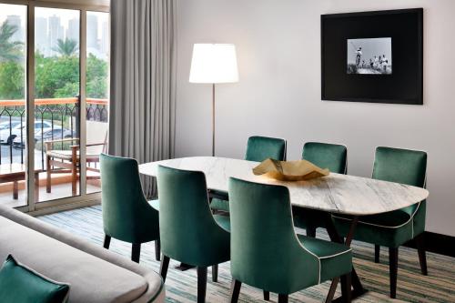 a dining room with a table and green chairs at Address Montgomerie in Dubai