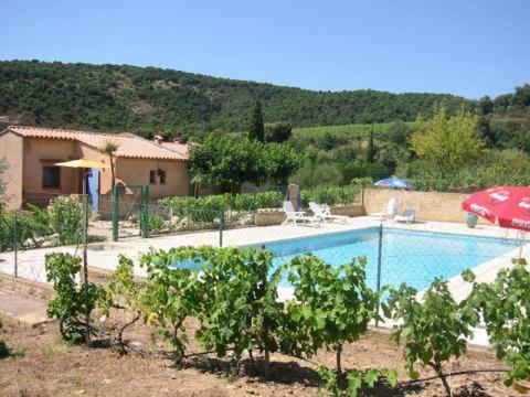 une piscine avec un parasol rouge et une maison dans l'établissement Les Oliviers, à Grimaud