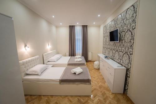 a bedroom with two beds and a tv on a wall at Center Deluxe Garni Hotel in Niš