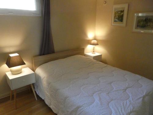 a bedroom with a bed and two night stands with lamps at Appartement Bardéron in Arcizans-Avant