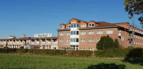 a large brick building in front of a field at Confour Hotel in Burgdorf