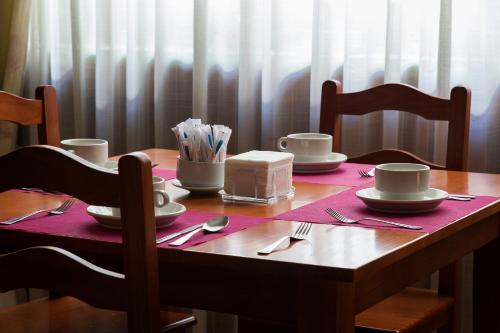 a wooden table with plates and cups and utensils at Hotel Castilla in Cáceres