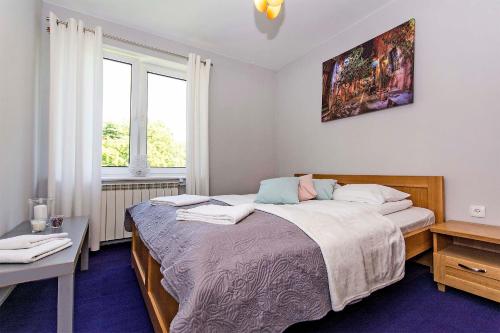 a bedroom with a bed and a desk and two windows at Green Park Rentyear Apartments in Sopot