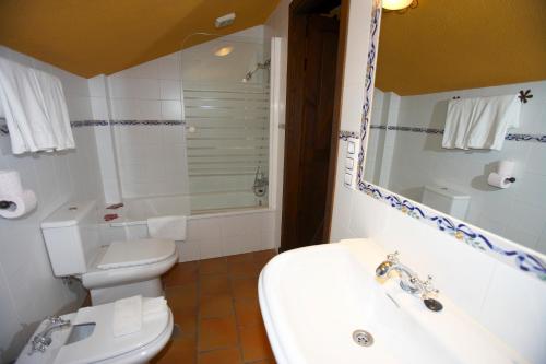 a bathroom with a white toilet and a sink at Hotel Posada San Antonio in El Bosque