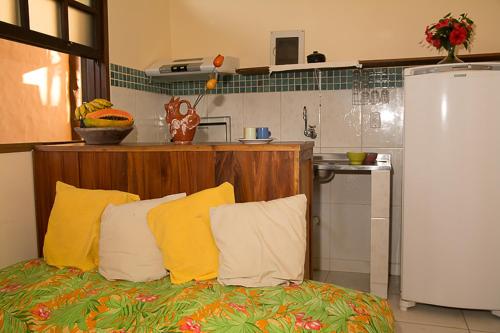 a kitchen with a couch with yellow pillows and a refrigerator at Trindade Hospeda - Casa 4 - Cantinho do Mar in Trindade