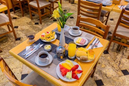 a table with plates of fruit and coffee on it at Hotel Vermont Ipanema in Rio de Janeiro