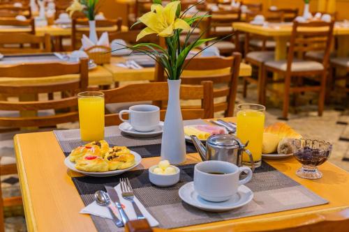 a table with breakfast foods and a vase of flowers at Hotel Vermont Ipanema in Rio de Janeiro