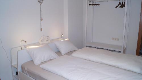 um quarto branco com 2 camas e almofadas brancas em Ferienwohnung Julius em Innsbruck