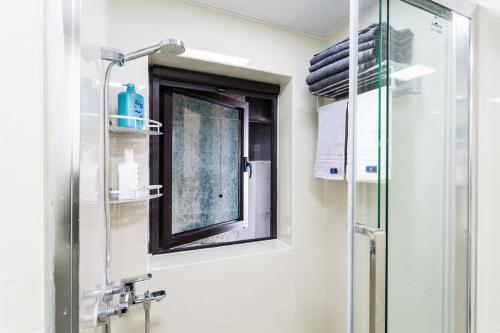La salle de bains est pourvue d'une douche et d'une fenêtre en verre. dans l'établissement Wuhan Hongshan·Jiedaokou· Locals Apartment 00116860, à Wuhan