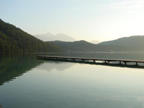 a bridge over a lake with mountains in the background at Parkhotel Zuzek in Sankt Kanzian