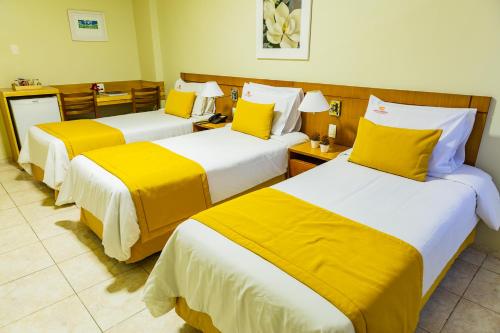 a hotel room with three beds with yellow pillows at Hotel Vermont Ipanema in Rio de Janeiro