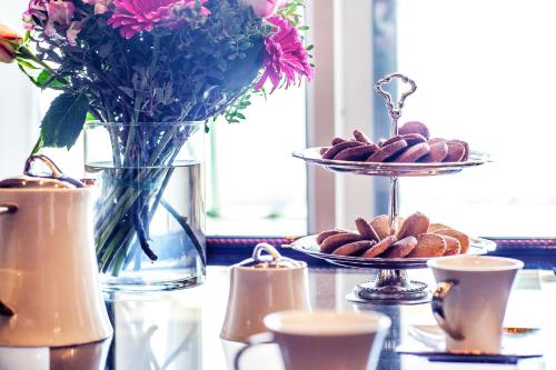 a table with a plate of cookies and a vase with flowers at Hotel Panorama in Thessaloniki
