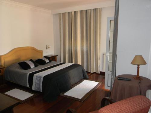 a bedroom with a bed and a table and a chair at Casa Estrada da Guia in Viana do Castelo