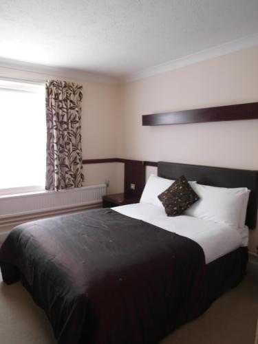 a bedroom with a large bed with a window at Best Western The George Hotel, Swaffham in Swaffham