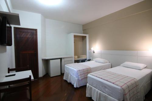 a hotel room with two beds and a desk at Samba Betim in Betim