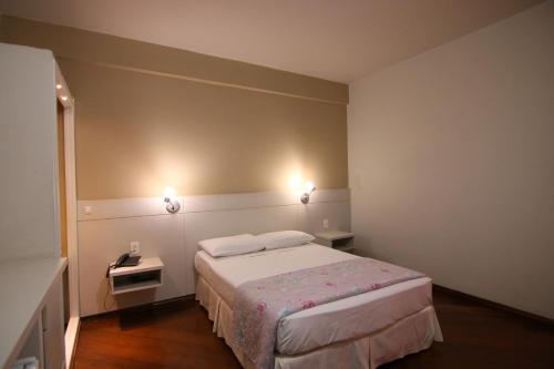 a bedroom with a bed and two lights on the wall at Samba Betim in Betim