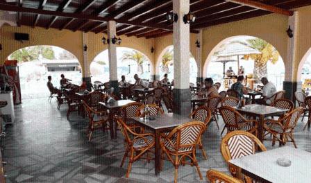 restauracja ze stołami i krzesłami oraz ludzie siedzący przy stołach w obiekcie Lemon Grove Hotels And Studios w mieście Kavos