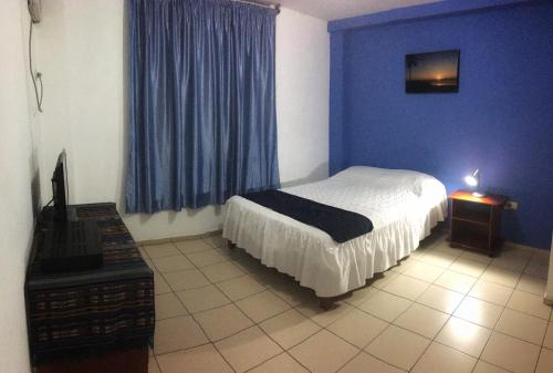 1 dormitorio con cama y pared azul en Hostal Albatros, en Manta