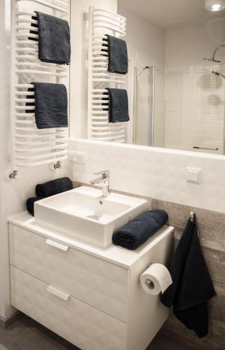 a white bathroom with a sink and a mirror at Apartamenty City Tower od WroclawApartament-pl in Wrocław