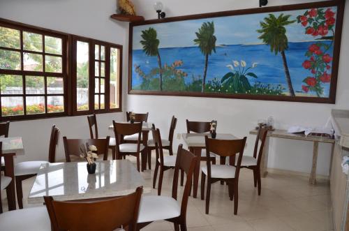 a restaurant with tables and chairs and a painting on the wall at Pousada Grauça in Cacha Pregos