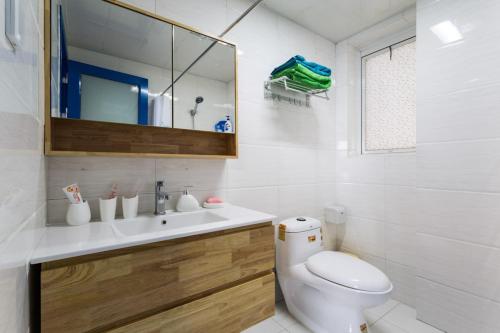 W łazience znajduje się toaleta, umywalka i lustro. w obiekcie Wuhan Jianghan·Hankou Railway Station· Locals Apartment 00120600 w mieście Wuhan