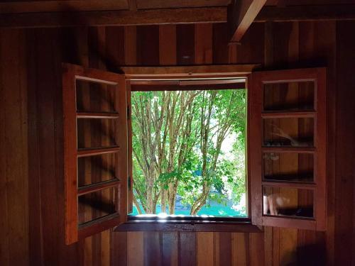 a window in a room with a view of a tree at Pousada Ypê das Montanhas in Monte Alegre do Sul
