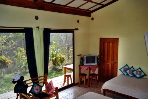 a bedroom with a bed and a balcony with a television at Fidelito Ranch & Lodge in Tambor