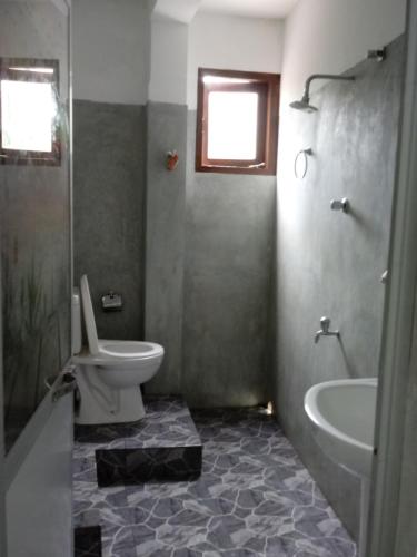 a bathroom with a toilet and a tub and a sink at Unawatuna Backpacker Lodge in Unawatuna