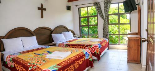 2 camas en una habitación con una cruz en la pared en Hotel Hacienda Xico Inn, en Xico