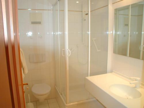 La salle de bains est pourvue d'une douche, de toilettes et d'un lavabo. dans l'établissement Kurhotel Würdinger Hof, à Bad Füssing