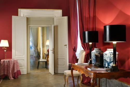 a room with red walls and a table with two lamps at Al Palazzo del Marchese di Camugliano Residenza d'Epoca in Florence