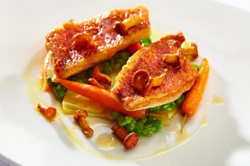 a white plate of food with peas and carrots at South Lodge in Lower Beeding