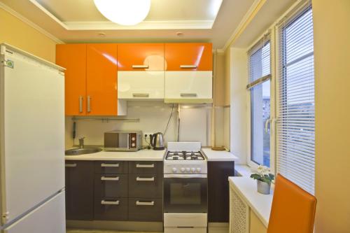 モスクワにあるLakshmi 1905 Apartmentのキッチン(オレンジと白のキャビネット、冷蔵庫付)