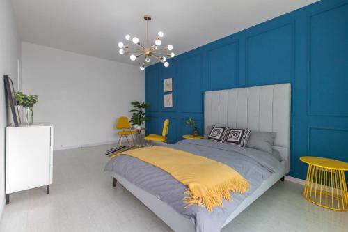 a bedroom with blue walls and a bed with a yellow blanket at Wuhan Wuchang·Wuchang River Beach· Locals Apartment 00139250 in Wuhan
