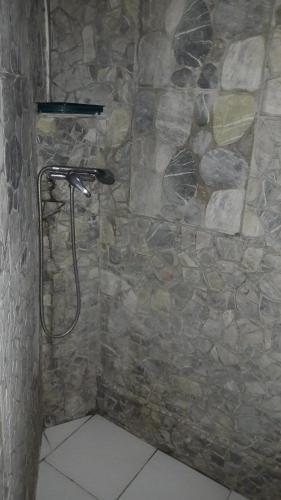 a bathroom with a shower with a stone wall at Meryem in La Trinité