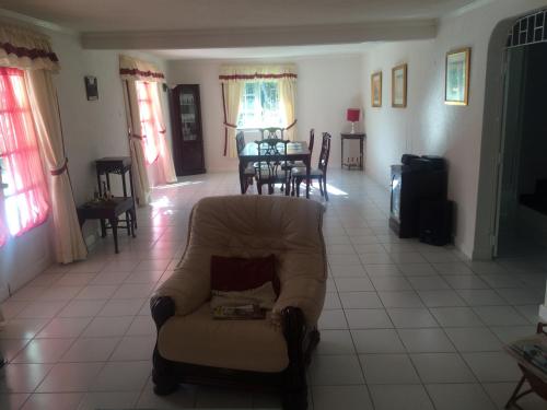 a living room with a chair and a table at Spacious White House Villa 1 minute to sandy beaches in Saint James