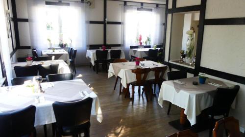 Un comedor con mesas y sillas con mantel blanco. en Hotel Zum Böhmegrund, en Bad Fallingbostel