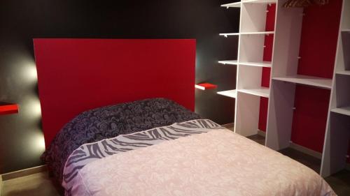 Le TilleulにあるGîte Le Tilleulのベッドルーム1室(赤いヘッドボードと白い棚付きのベッド1台付)