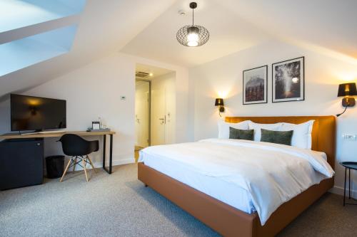 a bedroom with a large bed and a desk at UpperHouse Suites & More in Braşov
