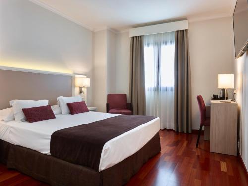 a hotel room with a large bed and a window at Hotel Maestranza in Ronda
