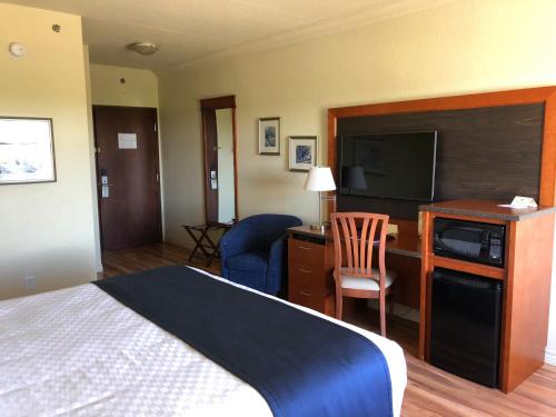 a hotel room with a bed and a desk with a television at Hotel L'Oie des neiges in Lévis