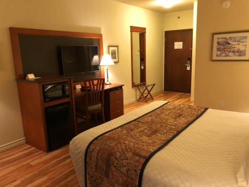 a hotel room with a bed and a flat screen tv at Hotel L'Oie des neiges in Lévis