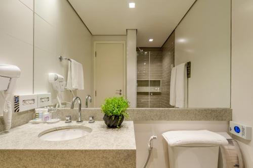 a bathroom with a sink and a toilet and a mirror at Mercure Sao Paulo Moema in Sao Paulo