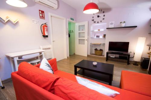 a living room with a red couch and a table at Apartamento Ciudad Monumental in Cáceres