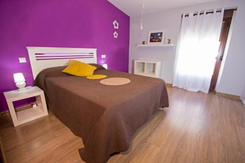 a purple bedroom with a bed with yellow pillows at Apartamento Ciudad Monumental in Cáceres
