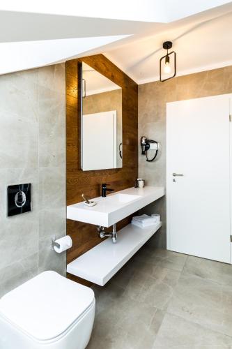 a bathroom with a white toilet and a sink at UpperHouse Suites & More in Braşov